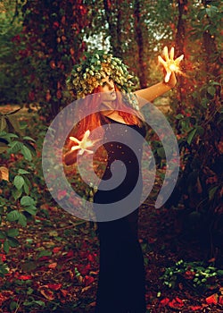 Fantastic young witch conjures in the forest photo