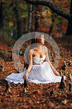 Fantastic young woman. beautiful fantasy girl fairy with white long dress in windy autumn park