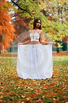 Fantastic young woman. beautiful fantasy girl fairy with white long dress in windy autumn park