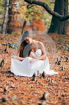 Fantastic young woman. beautiful fantasy girl fairy with white long dress in windy autumn park