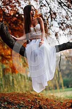 Fantastic young woman. beautiful fantasy girl fairy with white long dress in windy autumn park