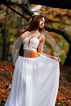 Fantastic young woman. beautiful fantasy girl fairy with white long dress in windy autumn park