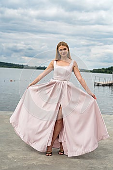 fantasy charming woman in elegant ping evening dress relaxing near lake