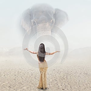 Fantasy fashion portrait of young woman posing in front of giant elephant
