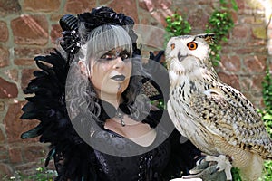 Fantasy figure. A woman dressed as a witch with an eagle owl on her hand