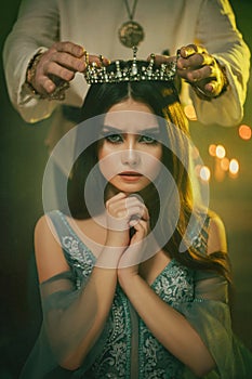 Fantasy medieval couple. Image of lovers - king and queen. hands of man put gothic crown on girl& x27;s head. Coronation of photo