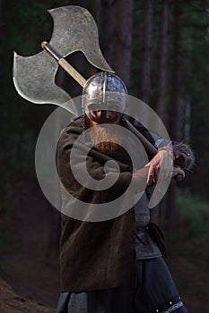 Fantasy medieval red-haired gnome warrior with beard with huge ax halberd in forest