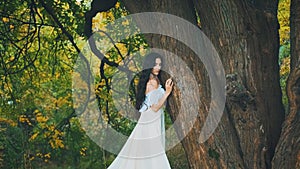 Fantasy mystery woman hug touching hand old tree trunk in dark forest