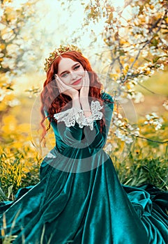 Fantasy portrait happy redhead woman queen in golden crown sitting on grass. Girl princess smiling face green vintage