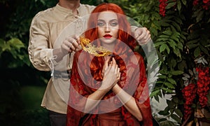 Fantasy portrait romantic couple in love man and woman, medieval style masquerade ball. gold carnival mask. Red-haired