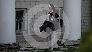 fantasy shot of sinful nun, lady in erotic gown is walking near old church, praying and strolling
