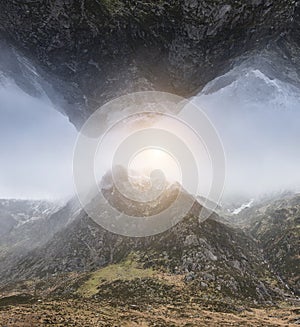 Fantasy surreal composite image of inverted mountain landscape above norma lmountain landscape with sun burst in sky inbetween