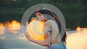 Fantasy woman embracing holding moon magic light glowing planet in hands hugs. Girl night elf beauty face fairy river