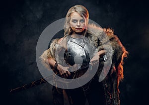 Fantasy woman knight wearing cuirass and fur, holding a sword scabbard ready for a battle. Fantasy fashion. Cosplayer as