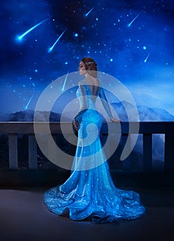 Fantasy woman princess stands on balcony looks at night sky space cosmos stars. Girl enjoy magic starfall ball. Elegant photo