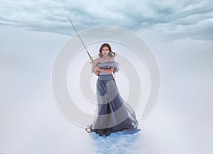 Fantasy woman princess warrior holding medieval iron sword in hands. Fairy tale snow queen. vintage gray blue dress