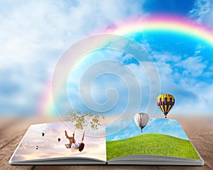 Fantasy worlds in fairytales. Book, hot air balloons and rainbow in cloudy blue sky on background