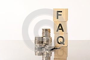 FAQ - Frequency Asked Questions - acronym on wooden cubes on white background with coins