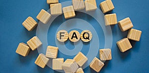 FAQ, frequently asked questions symbol. Wooden circles with word `FAQ, frequently asked questions`. Beautiful blue background.