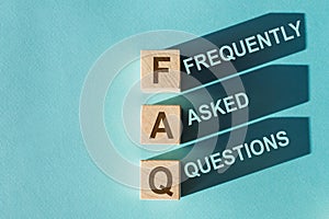 FAQ or Frequently Asked Questions text by wooden cubes on blue texture