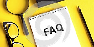 FAQ on a notebook with glasses, magnifier and pensil photo