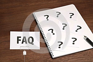 FAQ on a piece of paper and many question marks on notebook.