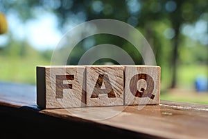 FAQ sign made of wooden cubes on table outdoors