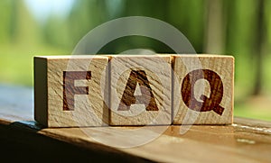 FAQ sign made of wooden cubes on table outdoors