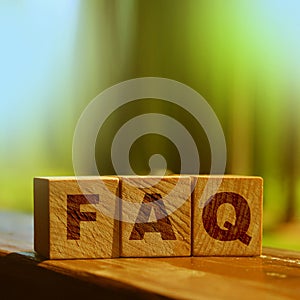 FAQ sign made of wooden cubes on table outdoors