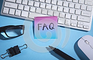 FAQ on sticky note with a computer keyboard and other objects