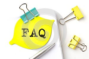 FAQ text on yellow sticker on notebook with pen