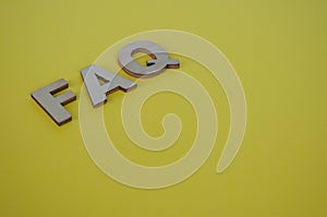 FAQ wooden letters on yellow background. Question and Answer concept