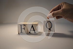 FAQ word from wooden cubes. Spot light and white background. Close up