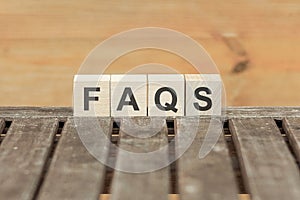 Faqs concept with wooden block on wooden table background