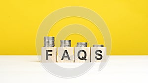 faqs - text on wooden cubes, yellow background. growing trend