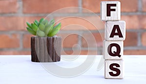 FAQS the word on cubes against the background of a brick wall with a cactus