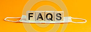 Faqs word written on wood block. faqs text on table, concept. yellow background