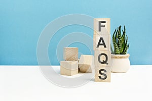 FAQS - word is written on wooden cubes on a blue background. close-up of wooden elements. In the background is a green