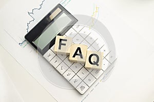 FAQS written on wooden cube with keyboard , calculator, chart,glasses.Business
