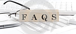 FAQS written on wooden cube with keyboard , calculator, chart,glasses.Business concept
