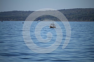 Far shot fishing boat on the water with shoreline in the horizon