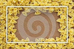 Farfalle macaroni background of pasta. A textured wooden cutting board. Close-up view from the top. Free space for text. With whit