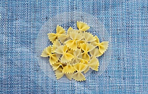 Farfalle macaroni A handful of macaroni on a rustic blue textured background. A view from the top, a close-up of a