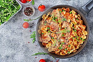 Farfalle pasta with chicken fillet, tomato sauce and green peas