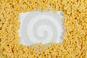 Farfalle pasta making a frame on rustic linen fabric