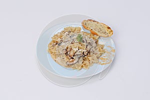 farfalle pasta with mushroom white cream sauce and garlic bread in a dish on an isolated background - Italian food style