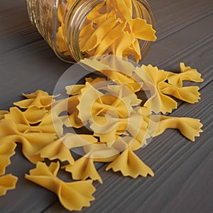 Farfalle pasta is randomly scattered on a wooden board