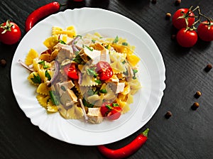 Farfalle pasta salad with chicken and vegetables in plate