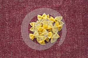 Farfalle macaroni A handful of macaroni on a rustic red-brown textured background. A view from the top, a close-up of a photo