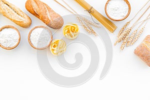 Farinaceous food. Fresh bread and raw pasta near flour in bowl and wheat ears on white background top view space for